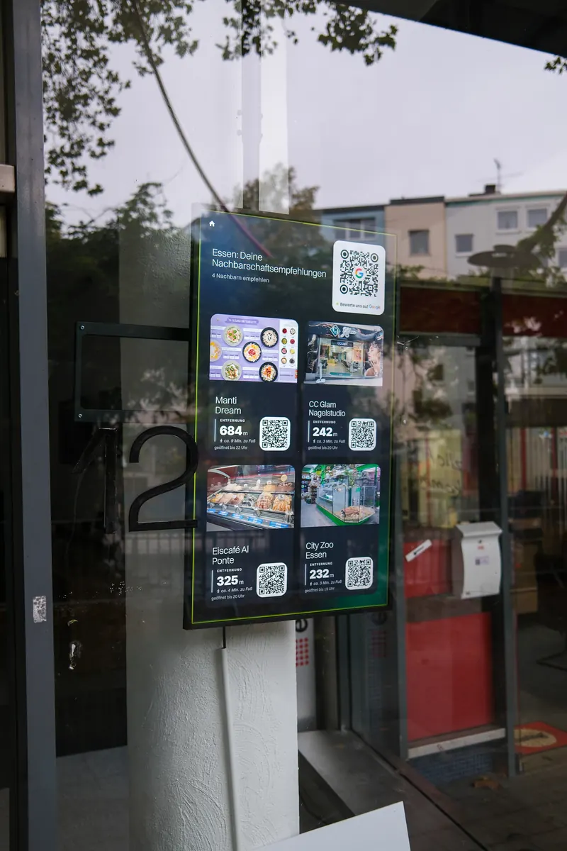 Großer Hochformat-Bildschirm im Schaufenster von Sterne.io am Kopstadtplatz, darauf vier Empfehlungen aus der Nachbarschaft